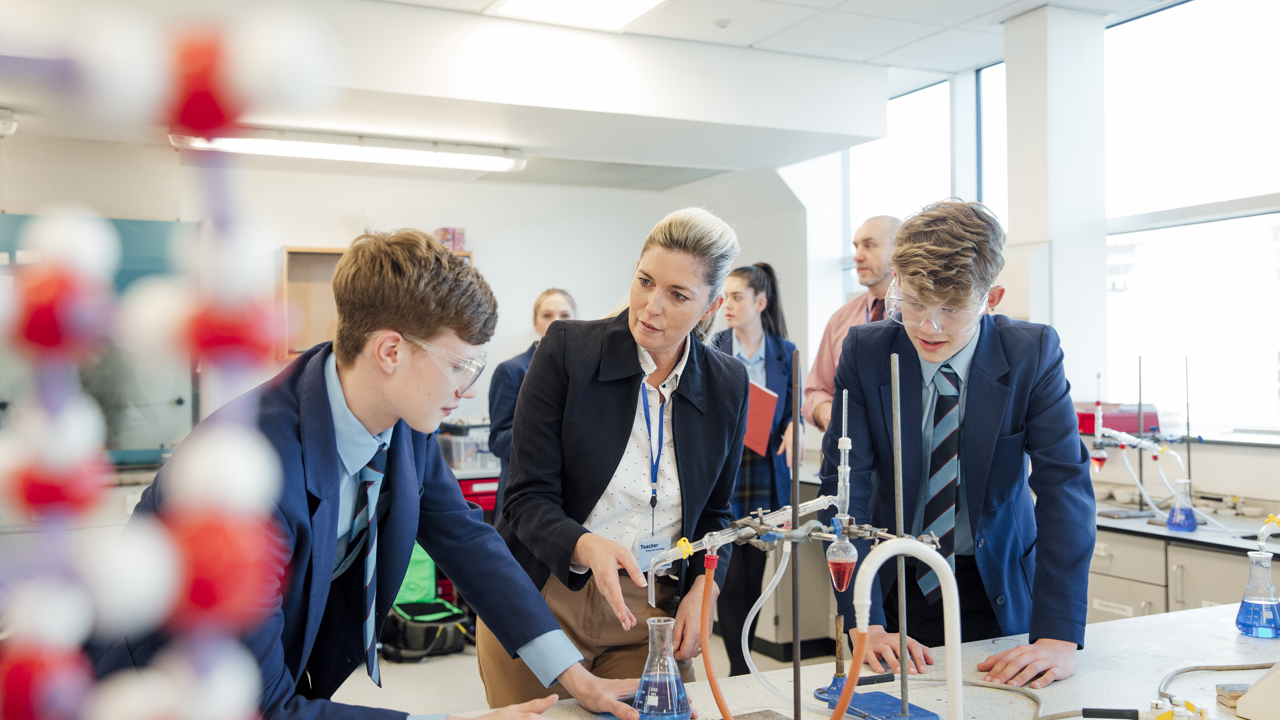 School science lab with pupils and teacher conducting an experiment 