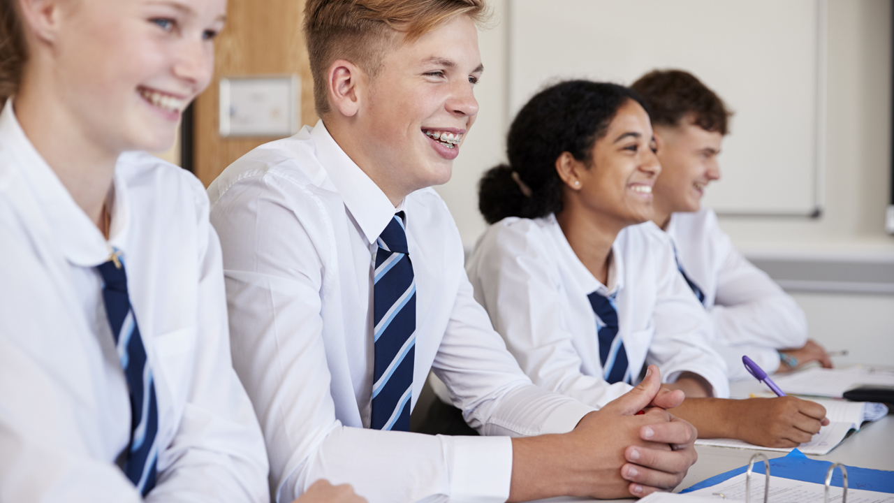Four students at their school desk smiling
