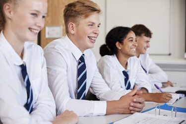 Four students at their school desk smiling