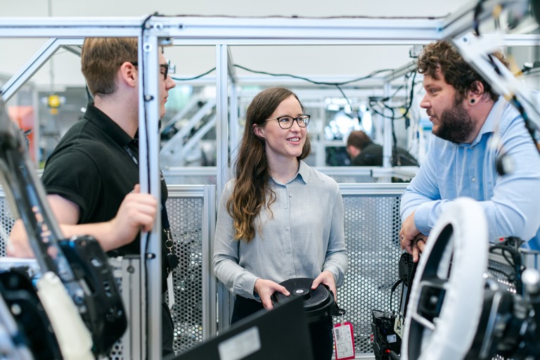 Two male and one female manufacturing engineers in the workshop discussing their work