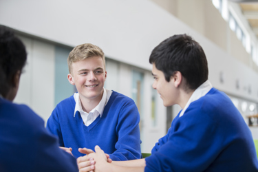 A group of secondary school boys in uniform are chatting