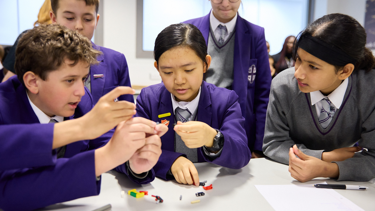 A group of young people around a table, they're using materials on the desk to build