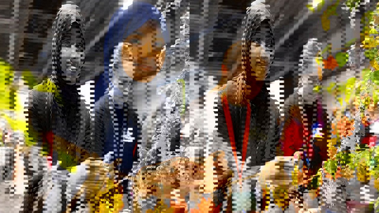 A young person at The Big Bang Fair interacts with coloured leaves at the Tree Council stand as they smile at the camera