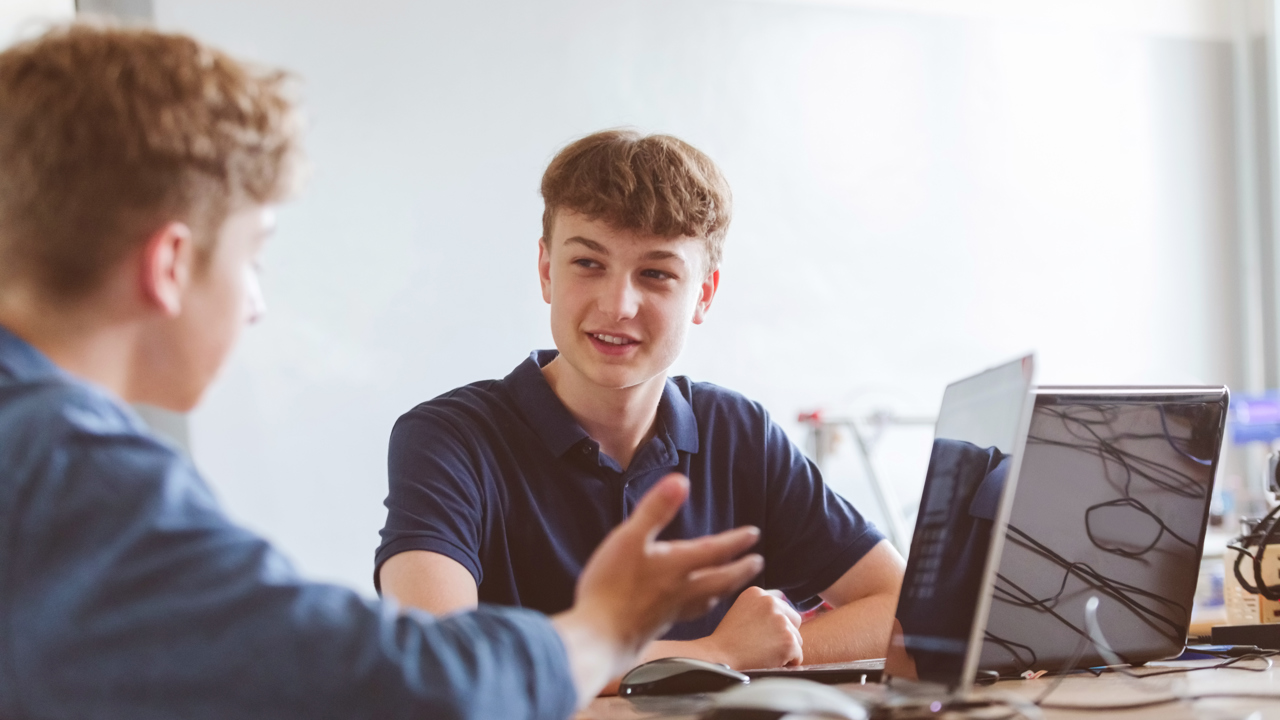 Two people look at screens at a desk