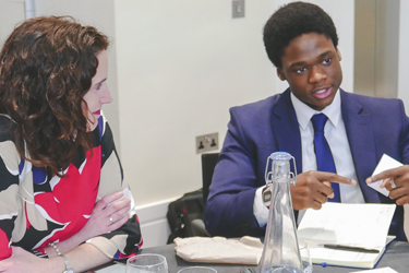 A professional and a student sit at a table discussing