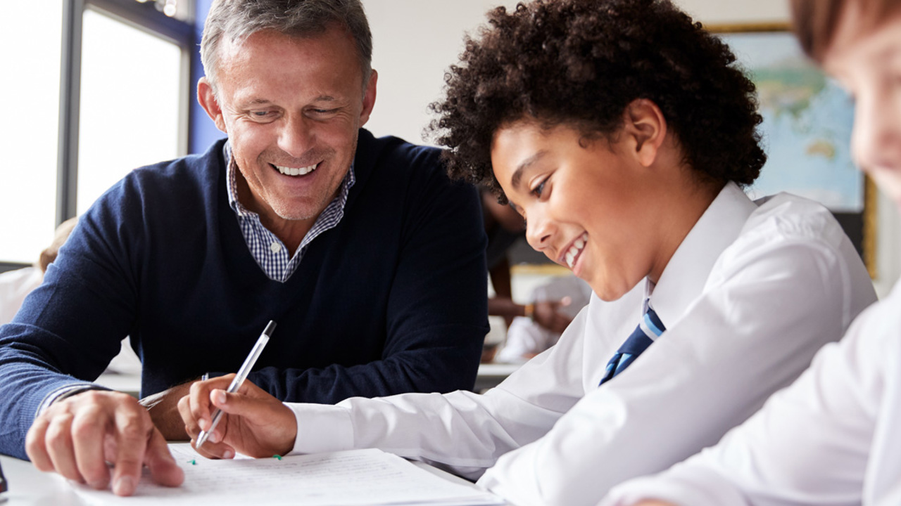A teacher talks to a young student about his work