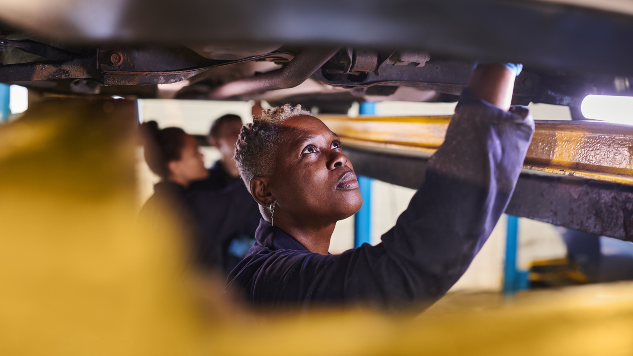 Three engineers pictured working under a vehicle