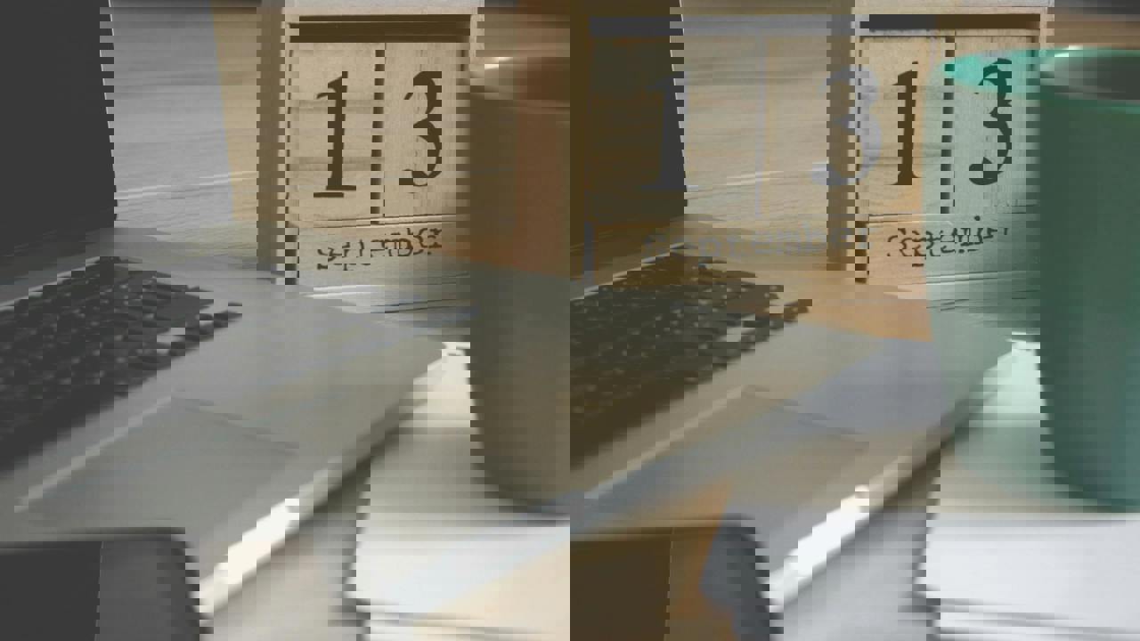 Laptop, phone, papers, mug and calendar on a desk